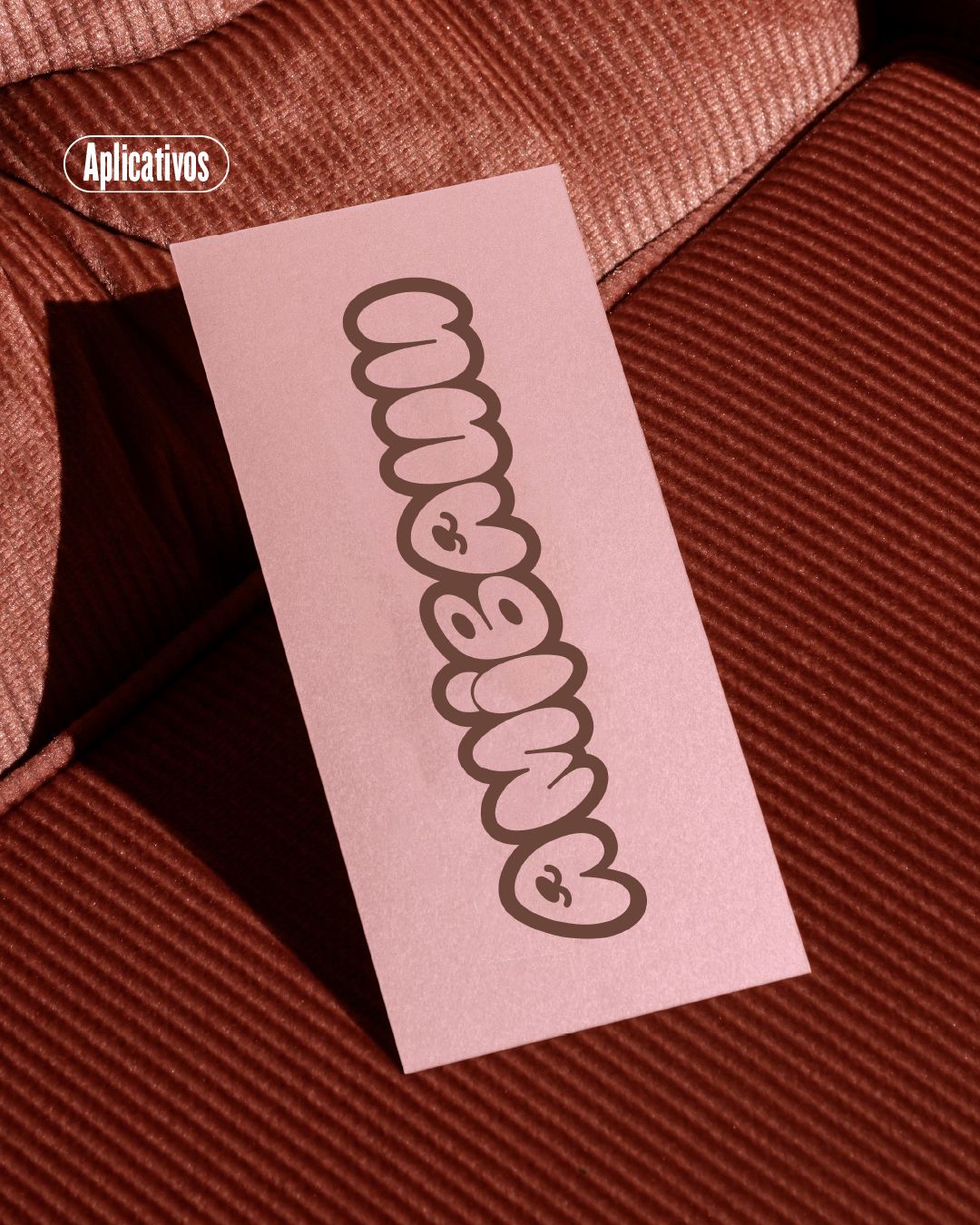Tarjeta rosa con el logo de AMIBAUU sobre una tela de pana terracota