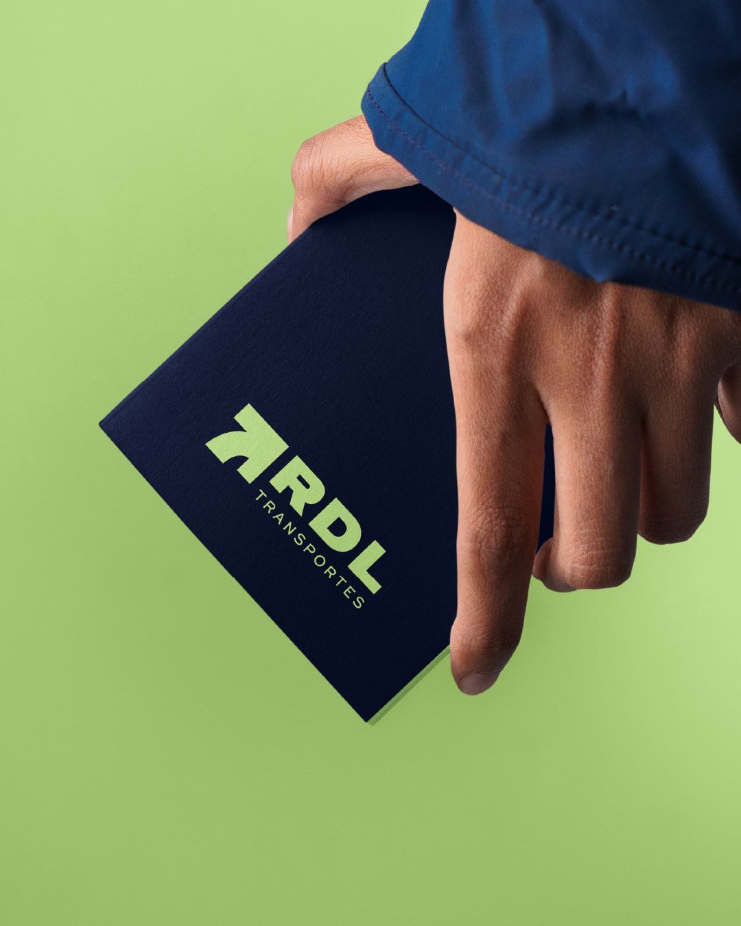 Mano sosteniendo una libreta azul marino con el logo de RDL Transportes sobre fondo verde